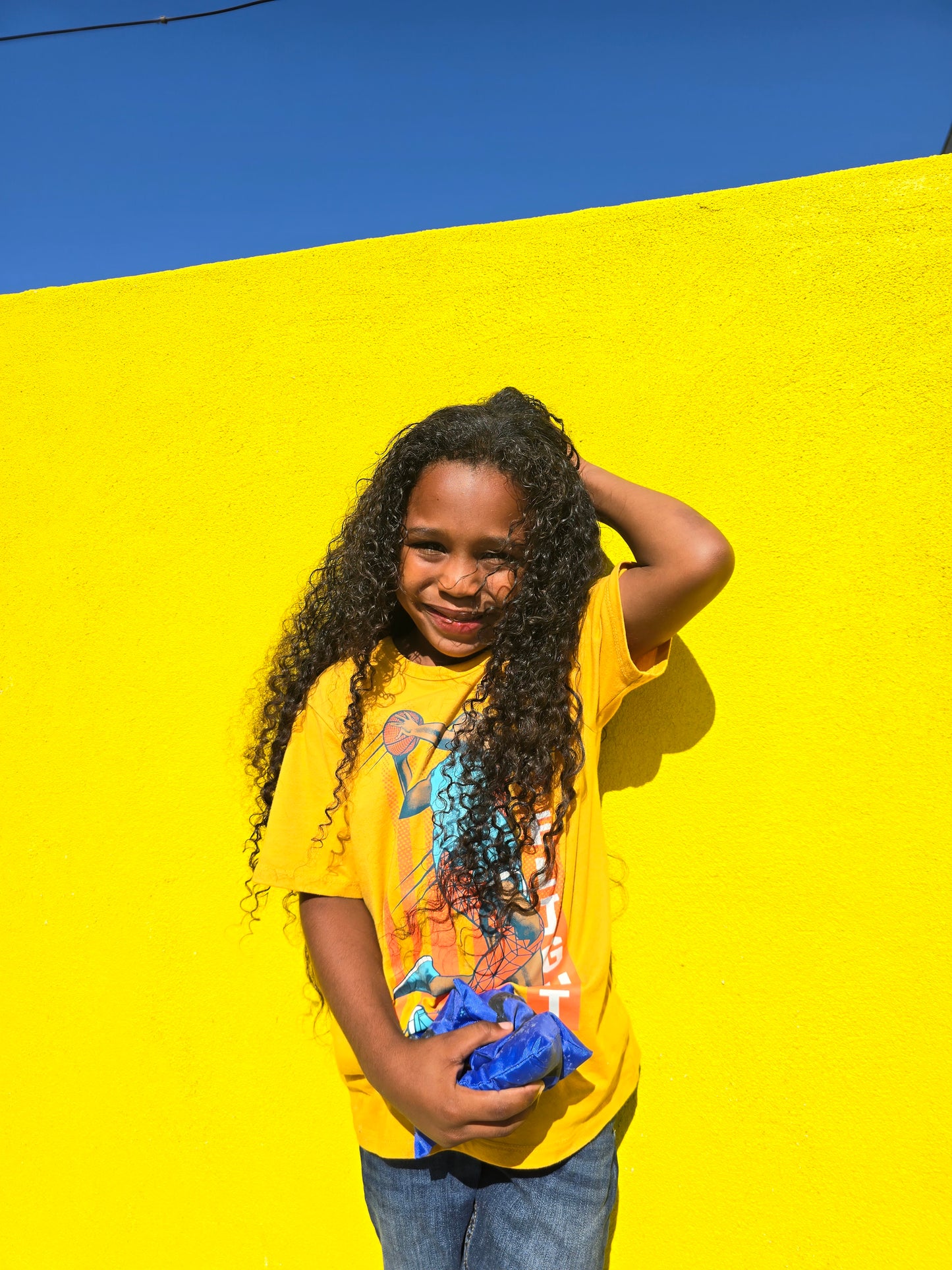 A young boy with long hair down his back using Guava & Blue Agave Curl Defining Mousse for frizz-free, bouncy curls with a natural finish.